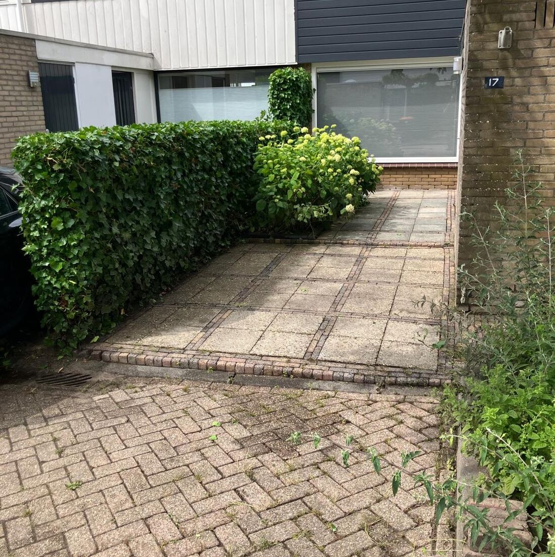 Een schoongemaakt terras met strak gesnoeide hagen bij een voordeur